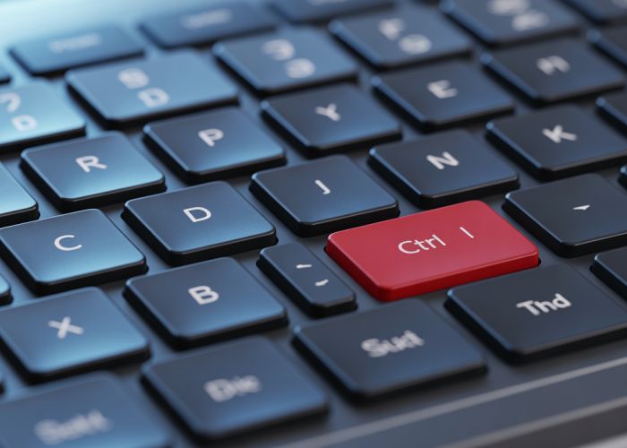 Fingers pressing Ctrl and I keys on a keyboard to italicize text.